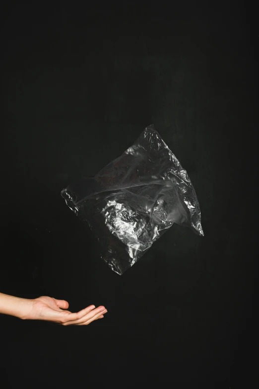 a woman holding a plastic bag in her hand, an album cover, inspired by Anna Füssli, pexels contest winner, conceptual art, meteorites, black paper, weightlessness, anish kapoor black