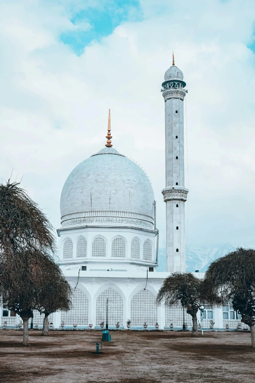 a large white building sitting on top of a lush green field, a marble sculpture, inspired by Abdullah Gërguri, trending on unsplash, arabesque, snowy peak, mosque, rounded roof, winter