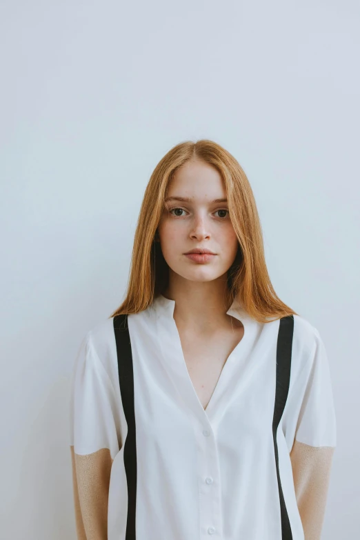 a woman standing in front of a white wall, a character portrait, by irakli nadar, trending on pexels, renaissance, cute young redhead girl, shoulder-long straight, fine white shirt, clean perfect symmetrical face