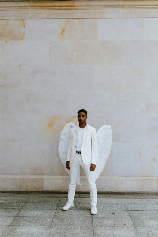 a man dressed as an angel standing in front of a wall, inspired by Louis Hersent, pexels contest winner, ashteroth, wearing suit, paris fashion week, white uniform