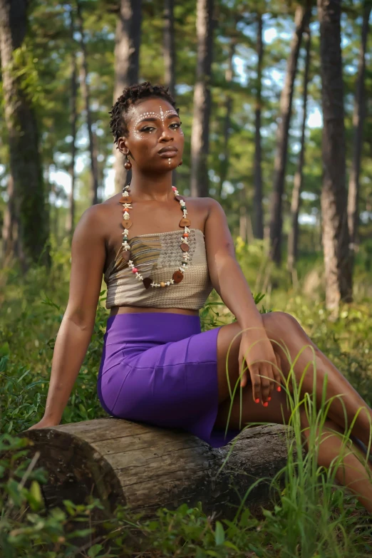 a woman sitting on a log in the woods, a portrait, by Lily Delissa Joseph, unsplash, purple halter top, brown skinned, in louisiana, wearing a tanktop and skirt