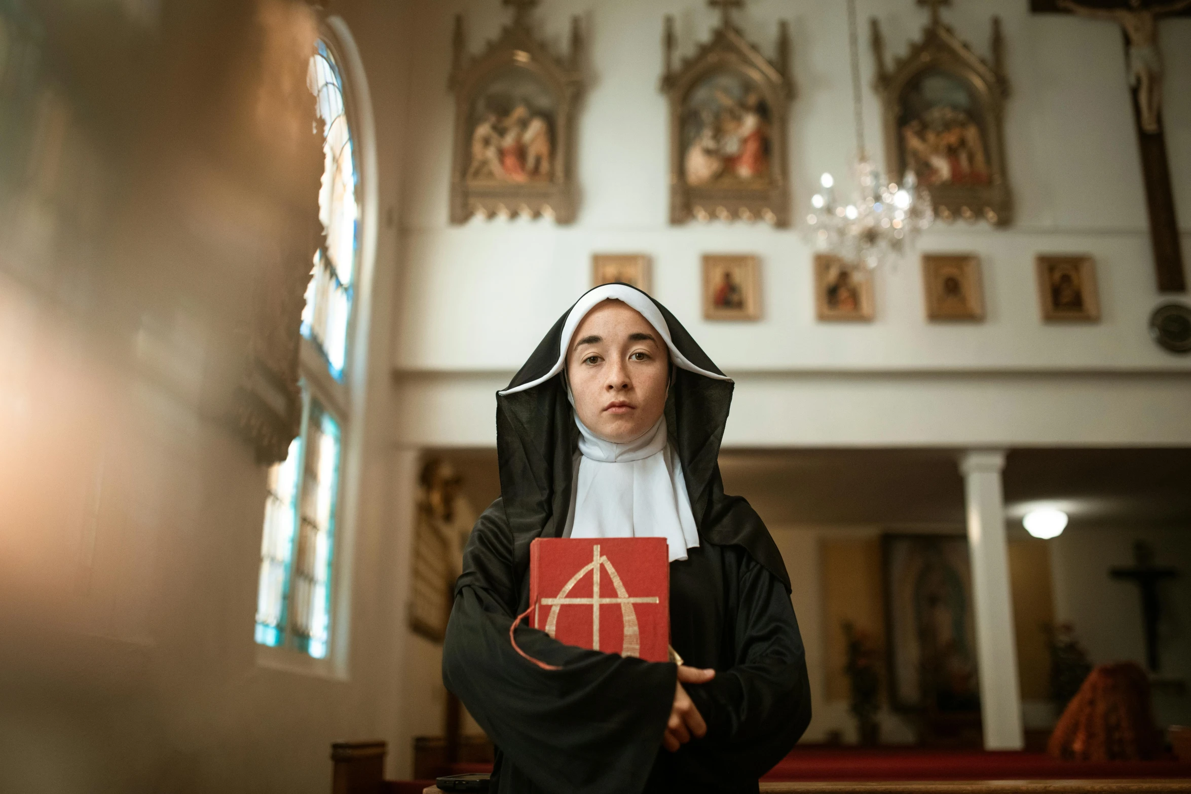 a nun holding a red book in a church, a portrait, pexels contest winner, serial art, an olive skinned, taejune kim, set photograph in costume, ( ( theatrical ) )