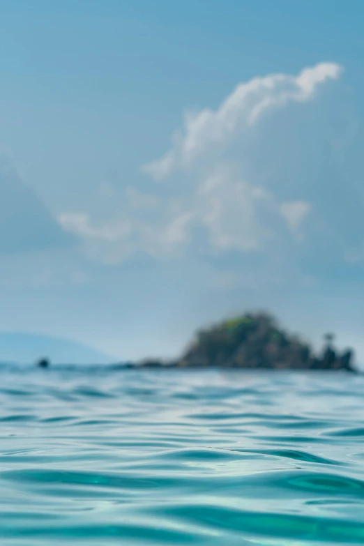 a body of water with a small island in the background, a picture, unsplash, visual art, background out of focus, viewed from the ocean, conde nast traveler photo, afternoon