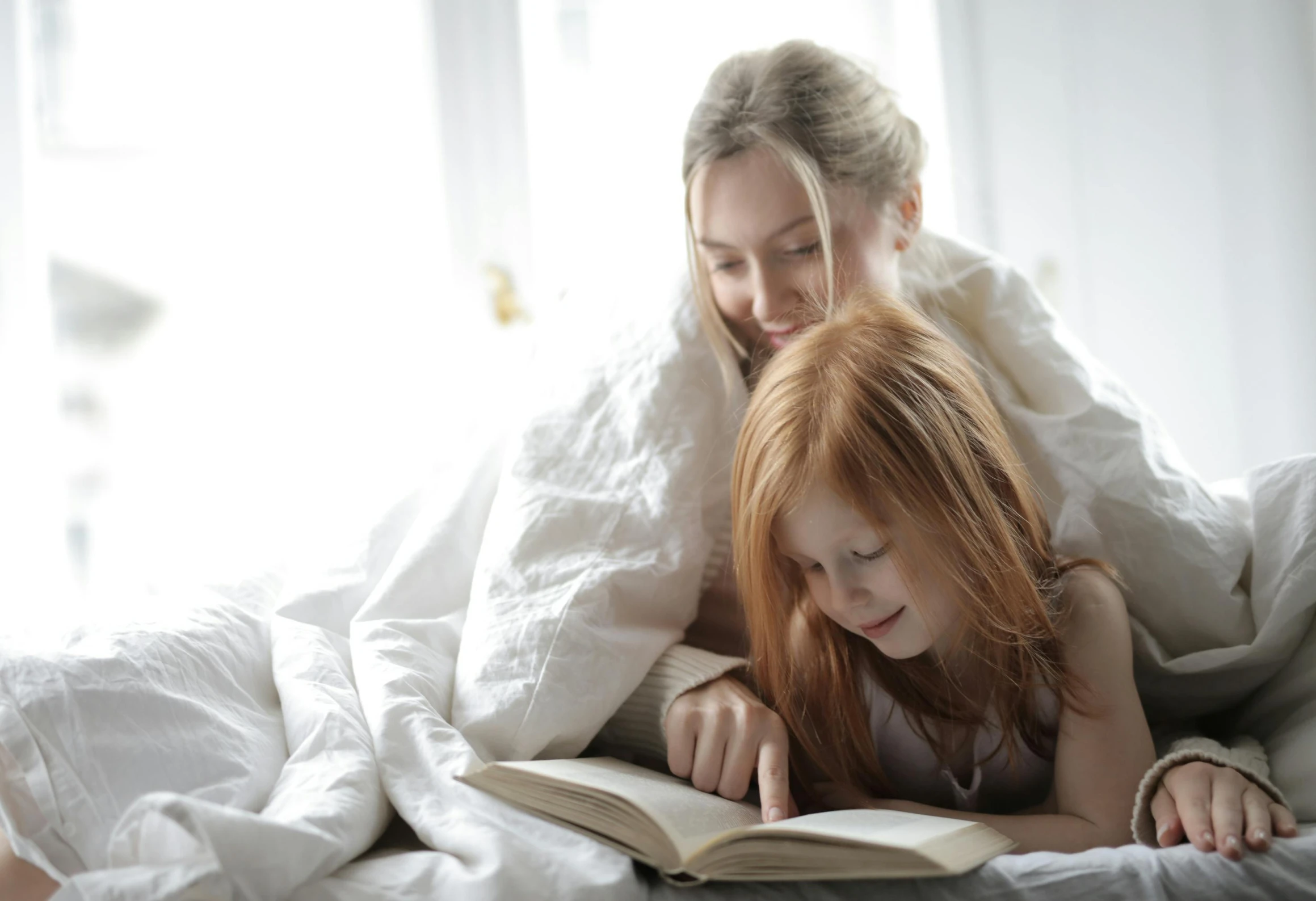 a woman and a little girl laying in bed reading a book, pexels contest winner, figuration libre, readhead, a blond, large)}], covered with blanket