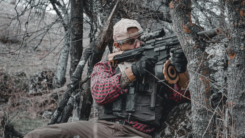 a man with a gun in a wooded area, unsplash, pulse rifles, sitting in a tree, tactical vest, game ready