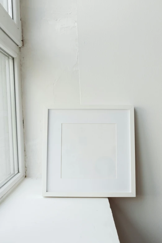 a picture frame sitting on top of a window sill, a minimalist painting, unsplash, studio photograph”, white gallery, square pictureframes, in 2 0 1 2