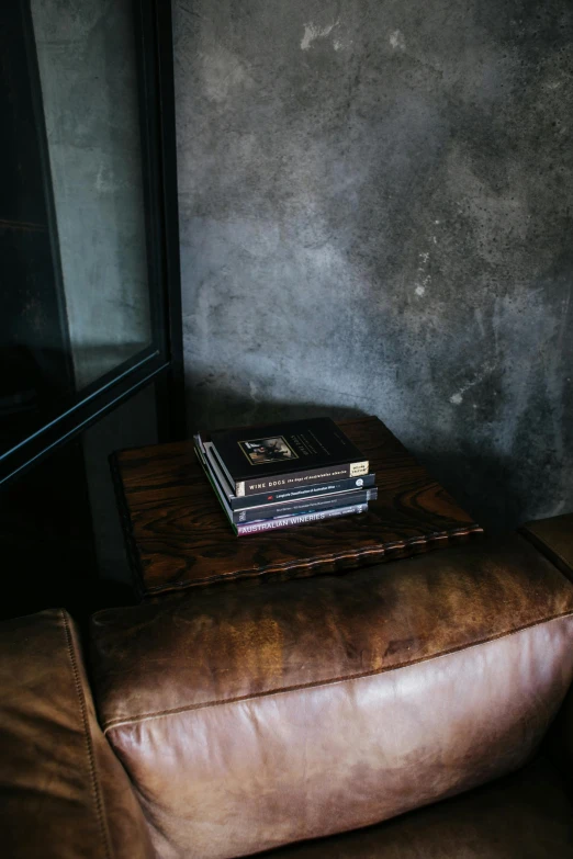 a brown leather chair with a stack of books on top of it, a portrait, unsplash contest winner, modernism, smouldering charred timber, luxurious wooden coffee table, high angle close up shot, dwell