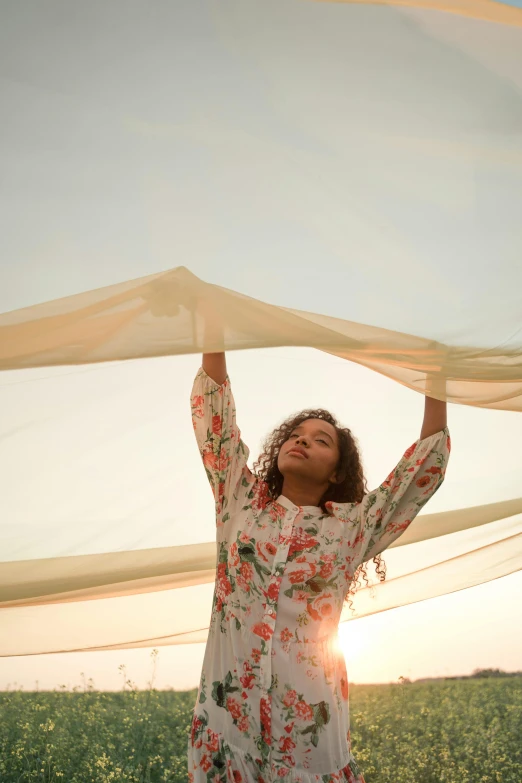 a woman holding a sheet over her head in a field, inspired by Christo, trending on unsplash, renaissance, with screens and silks, sunlit sky, imaan hammam, low-angle shot