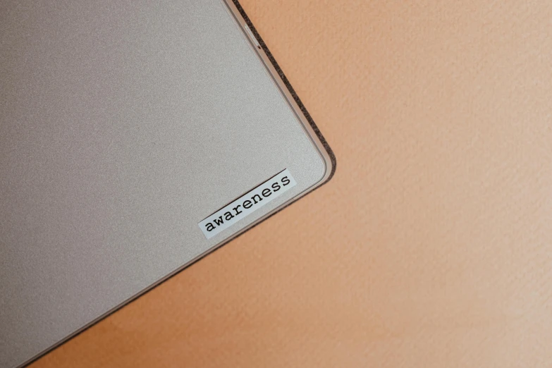 a laptop computer sitting on top of a wooden table, an album cover, trending on pexels, background image, silicone patch design, beige, awareness