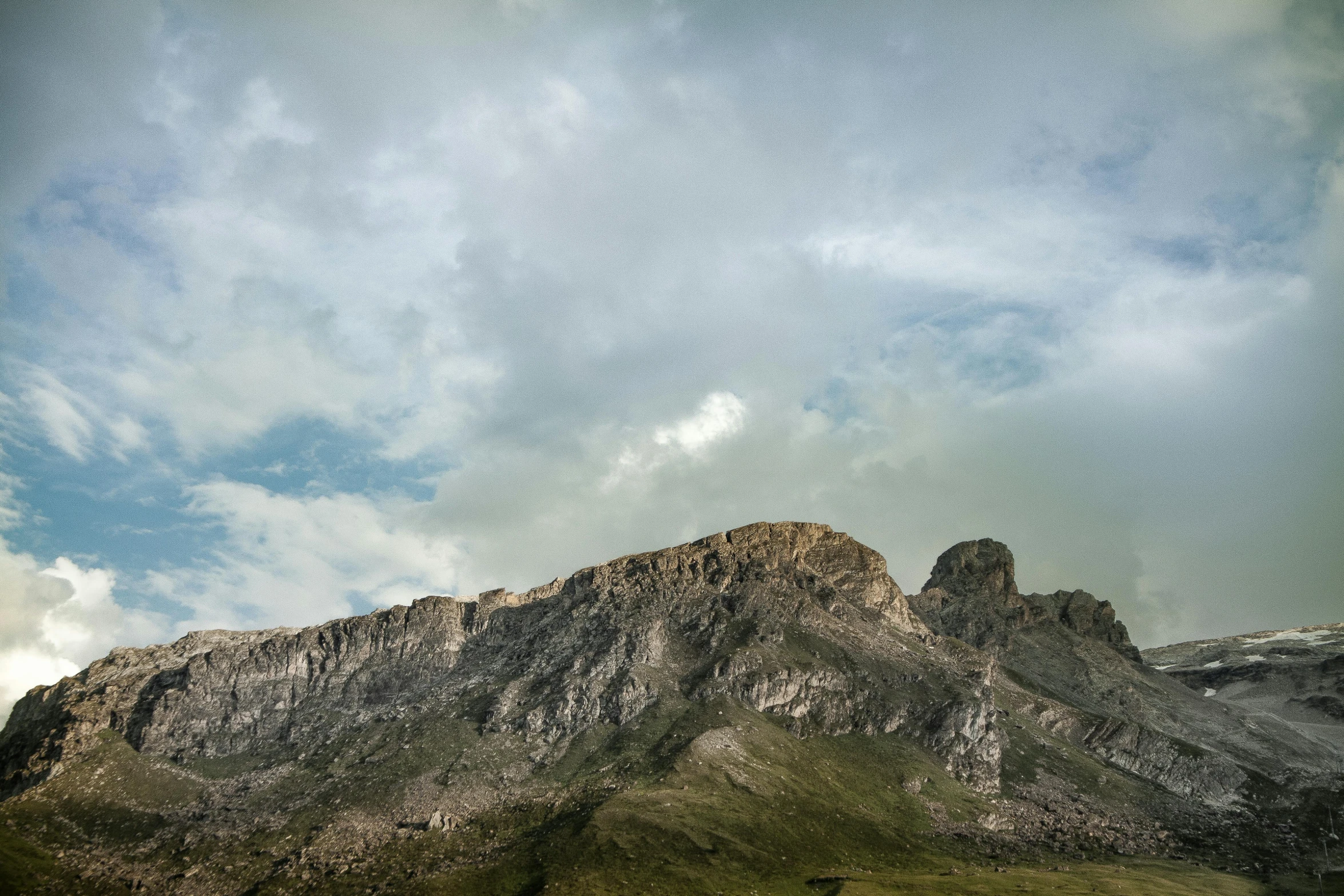 a herd of cattle standing on top of a lush green field, by Muggur, unsplash, les nabis, in socotra island, dark clouds above, rocky cliff, view from ground level