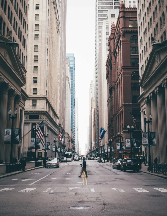 a person crossing a street in the middle of a city, by Maggie Hamilton, pexels contest winner, renaissance, modern chicago streets, old buildings, background image