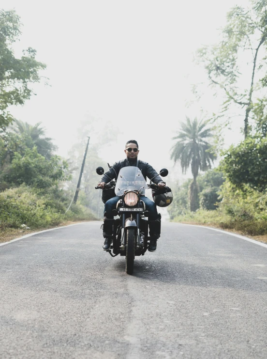 a man riding on the back of a motorcycle down a road, avatar image, 🚿🗝📝, full frame image, against the backdrop of trees