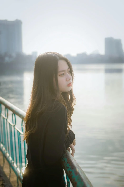 a woman standing in front of a body of water, by Tan Ting-pho, unsplash, realism, beautiful grumpy girl, in a city, mid long hair, song nan li