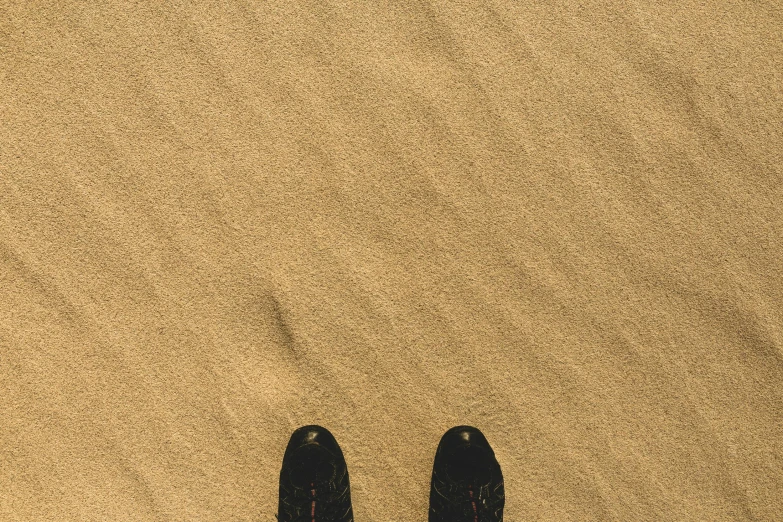 a person standing on top of a sandy beach, by Romain brook, postminimalism, running shoes, highly detailed # no filter, desert of distortion, yellow carpeted