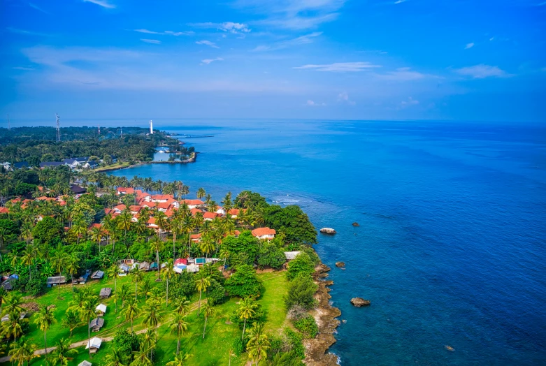 a large body of water next to a lush green hillside, by Aya Goda, pexels contest winner, hurufiyya, tropical coastal city, sri lanka, crystal clear blue water, white buildings with red roofs