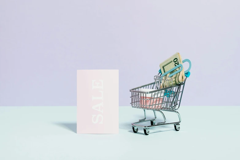 a shopping cart filled with money next to a sign, an album cover, by Julia Pishtar, trending on unsplash, pastel color theme, card, miniature product photo, blue and pink shift