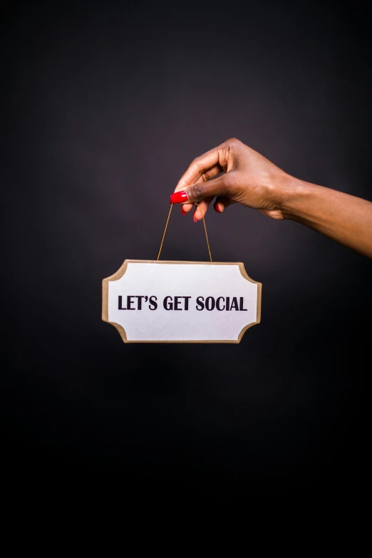 a hand holding a sign that says let's get social, by Arabella Rankin, cg society, happening, studio shoot, 1 9 2 0's style speakeasy, profile image, diverse