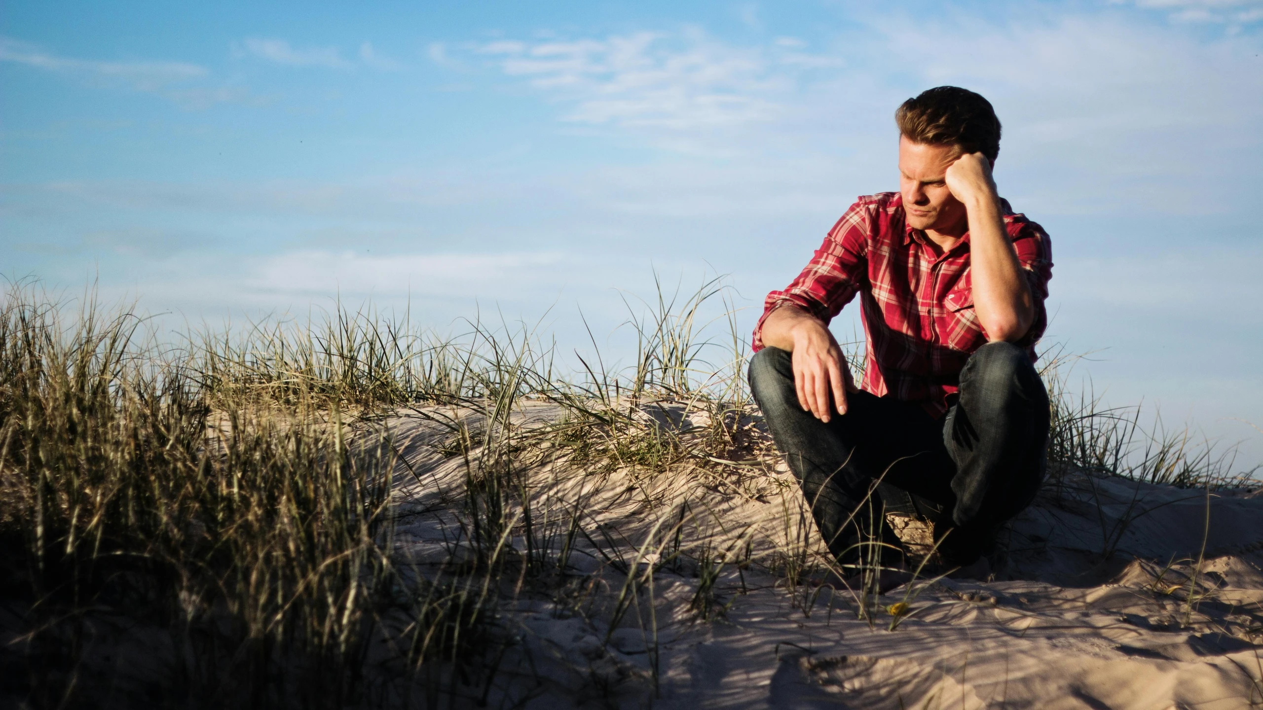 a man sitting on top of a sandy beach, by Eglon van der Neer, pexels, wearing a red lumberjack shirt, heartbroken, lachlan bailey, avatar image