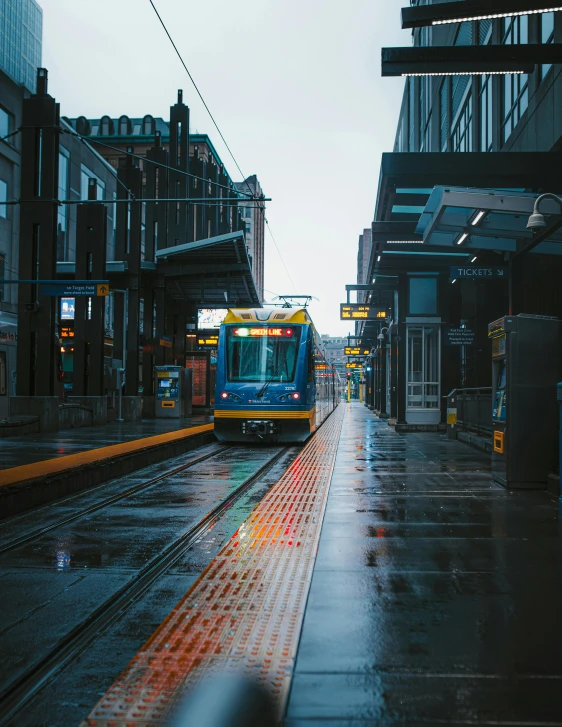 a train is coming down the tracks in the rain, by Carey Morris, unsplash contest winner, regionalism, street tram, blue and gold, lgbtq, seattle