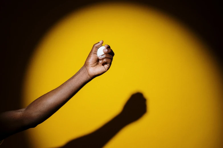 a person holding a baseball in their hand, by Andrew Domachowski, shades of yellow, ( ( dark skin ) ), coloured gel studio light, 15081959 21121991 01012000 4k