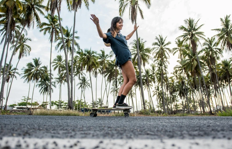 a woman riding a skateboard down a street, palm trees in the background, guide, fernanda suarez, lowres