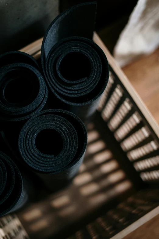 a stack of rolled up yoga mats sitting on top of a wooden crate, unsplash, private press, matte black, felt, 33mm photo