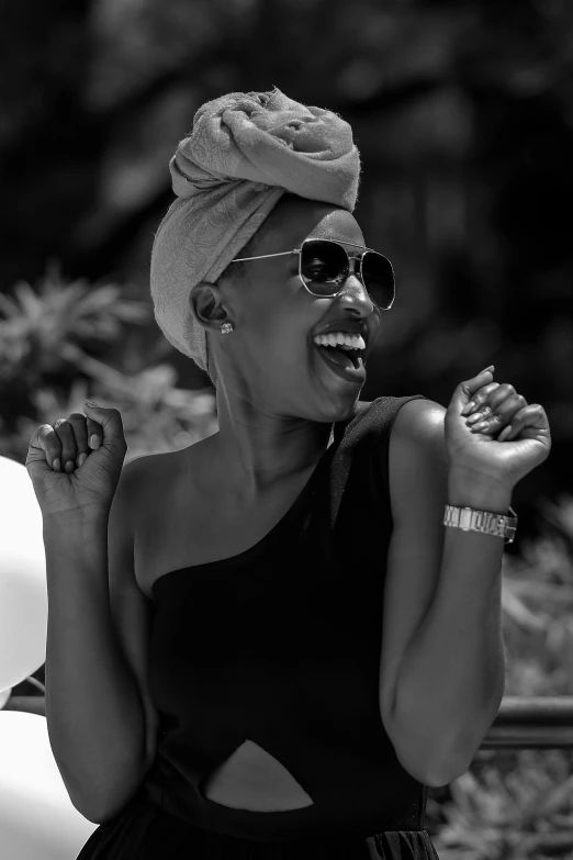 a black and white photo of a woman with a towel on her head, by Ceferí Olivé, pexels contest winner, afrofuturism, earing a shirt laughing, beret and sunglasses, lupita nyong'o, doing an elegant pose