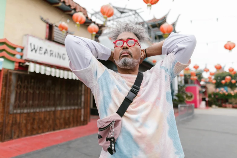 a man in a tie dye shirt holding a camera, trending on pexels, chinatown, silver hair and beard, tourist destination, wearing a baggy pajamas