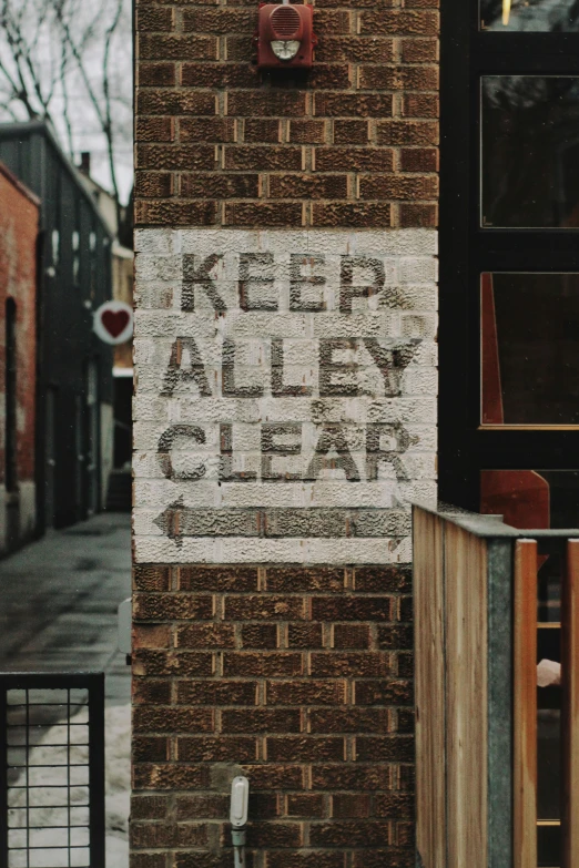 a brick building with a sign that says keep alley clear, by Jessie Algie, pexels, street art, background image, clear glass, album, small hipster coffee shop