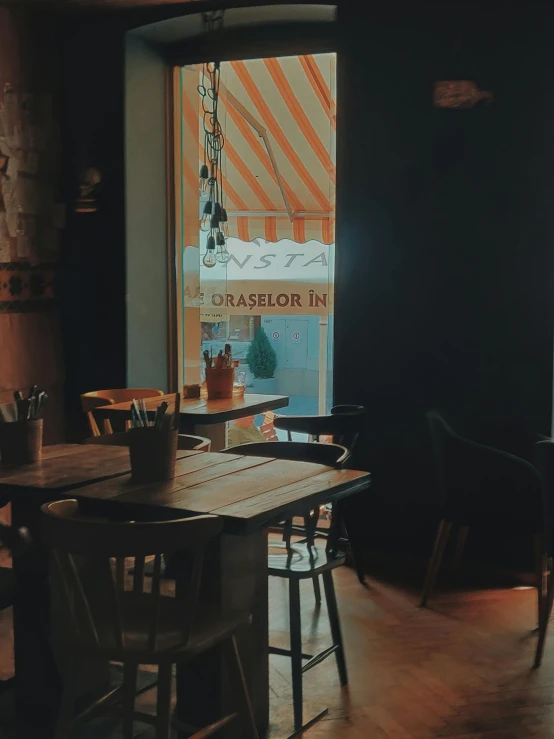 a wooden table sitting in front of a window, a screenshot, by Kristian Zahrtmann, trending on unsplash, cafe lighting, 90s photo, historical photo, restaurant!