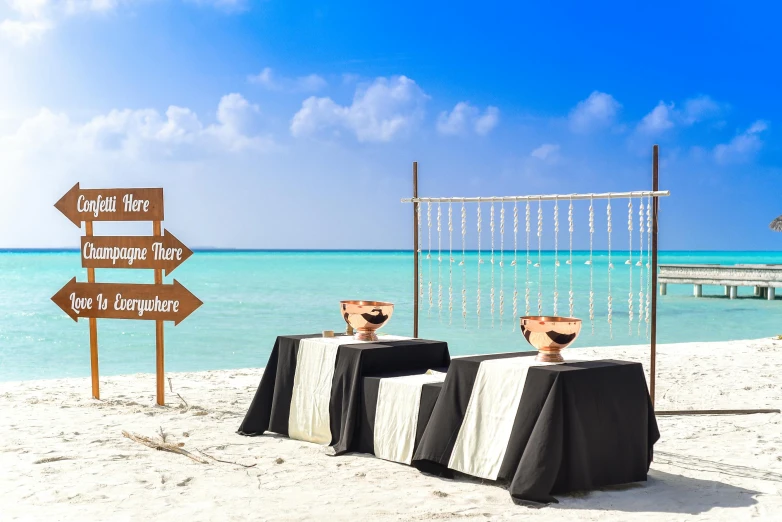 a couple of tables sitting on top of a sandy beach, black and aqua colors, square, decorations, profile image