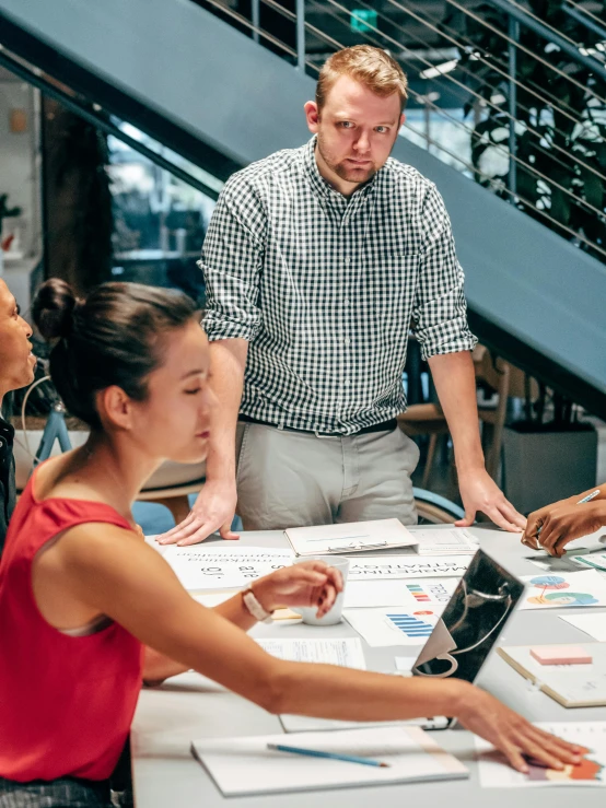 a group of people standing around a table, trending on unsplash, engineer, looking serious, high angle shot, avatar image