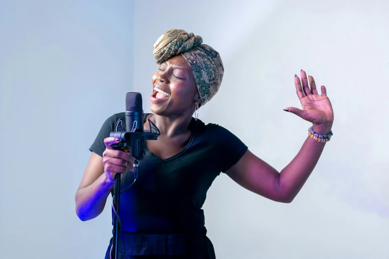 a woman in a black dress holding a microphone, by Ella Guru, pexels, happening, african sybil, avatar image, close - up studio photo, jamming to music