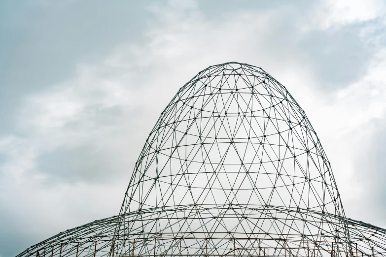 a large metal structure sitting under a cloudy sky, inspired by Buckminster Fuller, unsplash contest winner, magnificent oval face, mystical kew gardens, half textured half wireframe, an egg