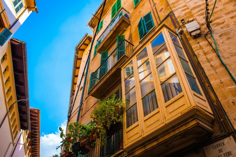 a couple of buildings that are next to each other, by Tom Wänerstrand, pexels contest winner, art nouveau, traditional corsican, vibrant greenery outside, golden windows, brown