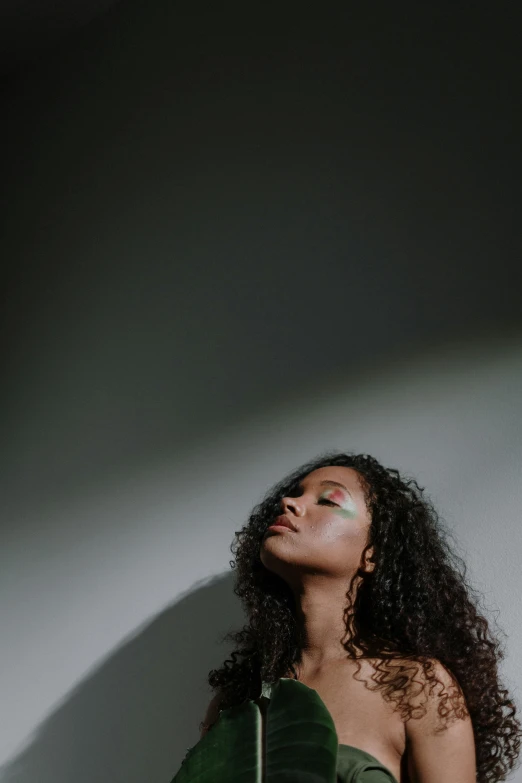 a woman in a green dress posing for a picture, an album cover, trending on pexels, light and space, black young woman, head looking up, curls, iridescent skin