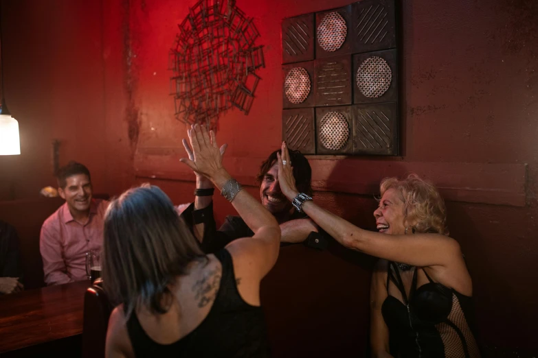 a group of people sitting at a table with their hands in the air, burlesque, rebirth rituals, underground party, 40 years old women