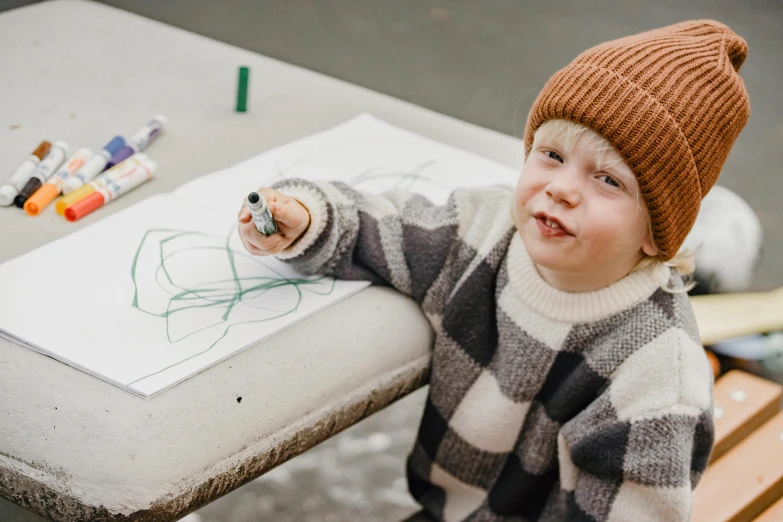 a little boy sitting at a table drawing on a piece of paper, a child's drawing, by Emma Andijewska, pexels contest winner, at the park, thick line drawing, casually dressed, toddler