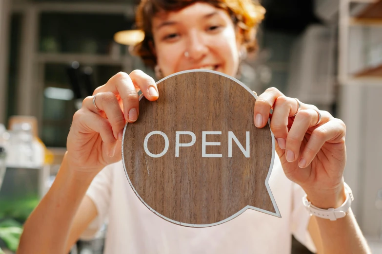 a woman holding an open sign in front of her face, trending on pexels, art & language, award winning shopfront design, a wooden, open plan, thumbnail