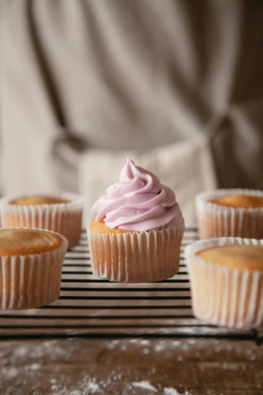 a bunch of cupcakes sitting on top of a cooling rack, a portrait, unsplash, photorealism, soft blush, purple, whipped cream, epicurious