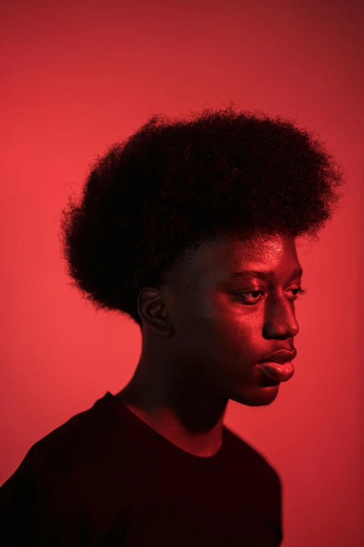 a man with an afro standing in front of a red background, inspired by Xanthus Russell Smith, pexels contest winner, portrait of depressed teen, in a black room, portrait androgynous girl, soft light from the side