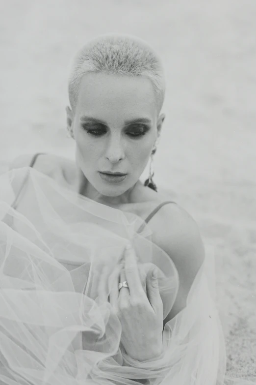 a woman sitting on top of a sandy beach, a black and white photo, inspired by Peter Lindbergh, unsplash, portrait of albino mystic, chaumet style, concert, natali portman