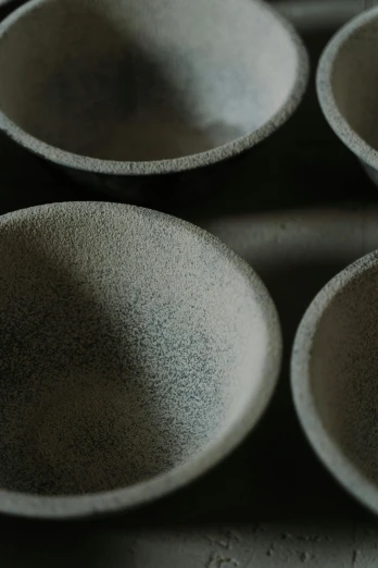 a group of bowls sitting on top of a table, an abstract sculpture, inspired by Maruyama Ōkyo, trending on unsplash, detail texture, graphite, upclose, powder