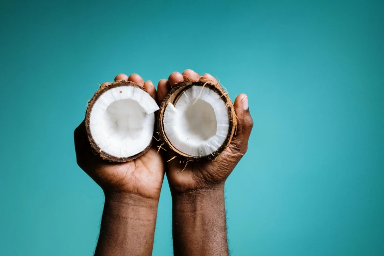 a person holding two halves of a coconut, by Carey Morris, trending on unsplash, hurufiyya, black man with afro hair, teal aesthetic, background image