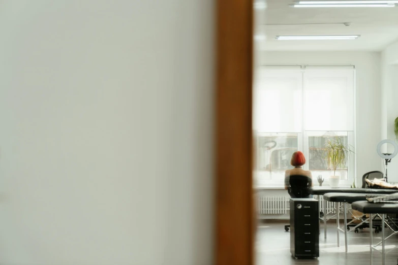 a woman sitting at a desk in an office, inspired by Elsa Bleda, pexels contest winner, realism, view from behind mirror, minimalist photorealist, woman with red hair, inside white room