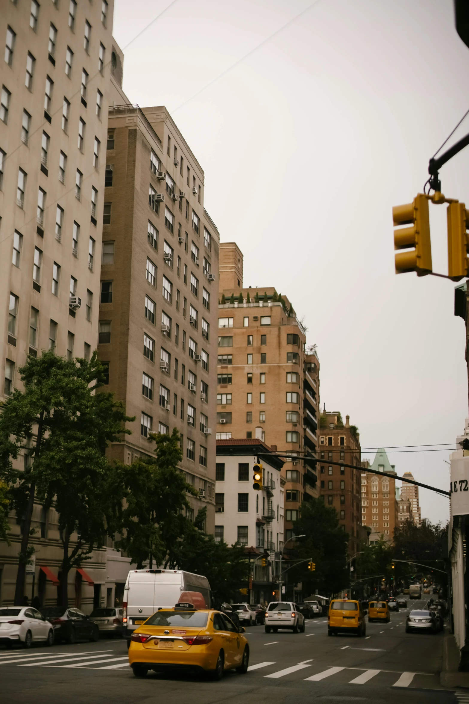 a street filled with lots of traffic next to tall buildings, a picture, unsplash, american barbizon school, overcast gray skies, yellow street lights, rundown new york apartment, a blond