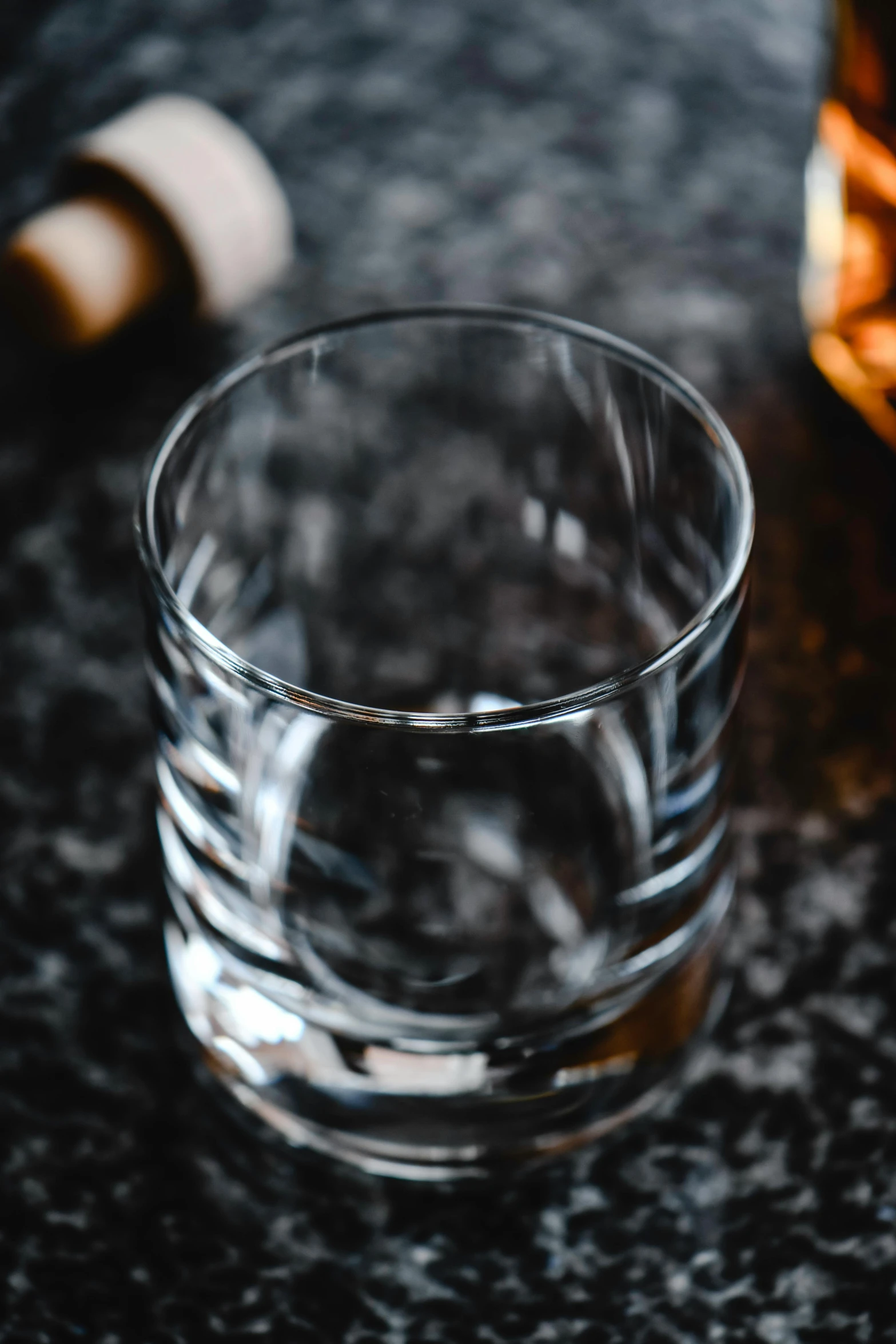 a glass of whiskey next to a bottle, unsplash, texture detail, glass tableware, multiple stories, far view