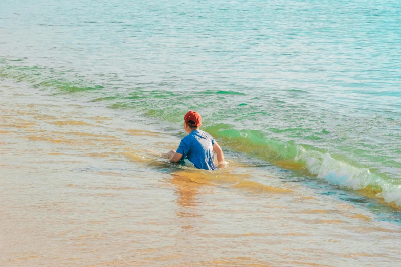 a man riding a wave on top of a sandy beach, pexels contest winner, lake blue, man sitting facing away, multicoloured, shallow water