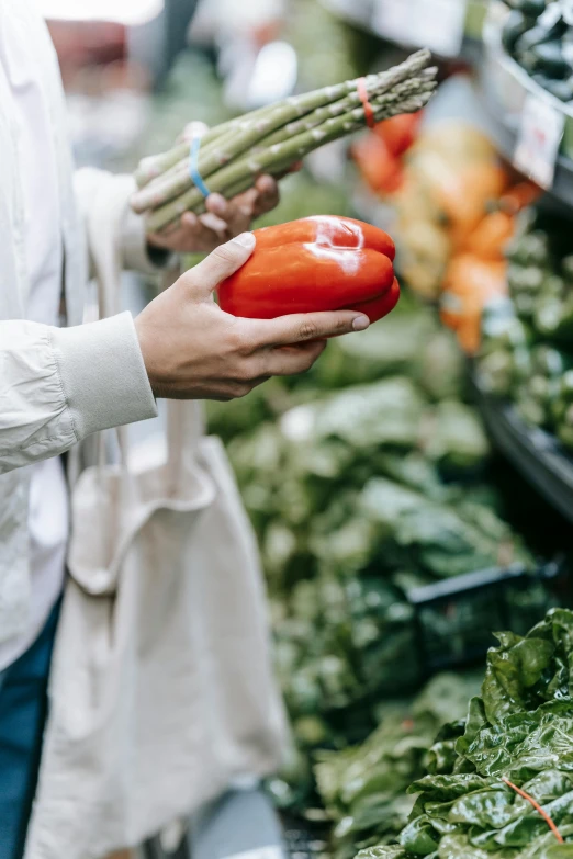 a woman holding a red pepper in her hand, by Everett Warner, pexels, renaissance, inside a supermarket, greens), 8 l