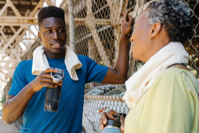 a man standing next to a woman holding a bottle of water, by Fletcher Martin, pexels contest winner, happening, man is with black skin, wearing fitness gear, nearest neighbor, avatar image